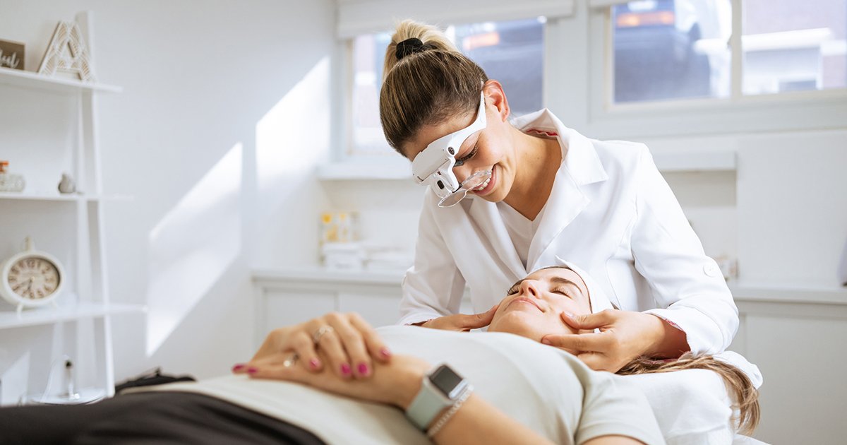 Dermatologist examining a patient's facial skin through magnifying loupes
